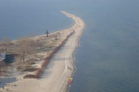 Półwysep w Rewie z krzyżem i plażą. Atrakcje turystyczne tego miejsca przyciągają spacerowiczów.