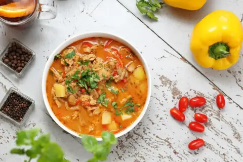 Aromatic gulasz, idealny na dietę trzustkową, z kawałkami mięsa, ziemniaków i papryki, ozdobiony natką pietruszki.