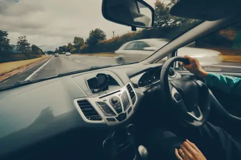 Widok z samochodu podczas jazdy po Polsce. Na desce rozdzielczej widoczny uchwyt na telefon. W tle droga i inne pojazdy. Dowód V5C rejestracja w Polsce.