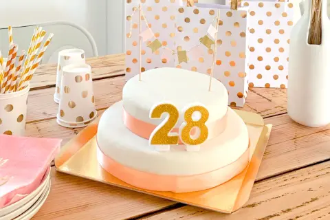 Tort urodzinowy z cyframi 28, ozdoby i prezenty na drewnianym stole.