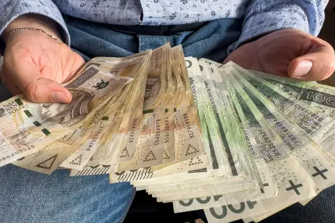 Dłoń trzyma plik banknotów. Czy darowizna a podatek to temat, który Cię interesuje?