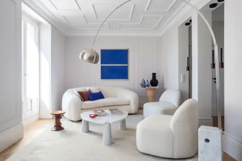 Sofá blanco y sillones acogedores, mesa de centro de mármol y arte abstracto azul. Ideas para decorar paredes salón.