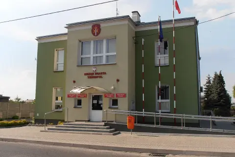 Urząd Miasta Terespol z polską i unijną flagą. Budynek ma zielono-żółtą elewację.