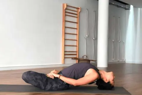 Mujer en postura de yoga Matsyasana, disfrutando de la apertura de pecho yoga beneficios.
