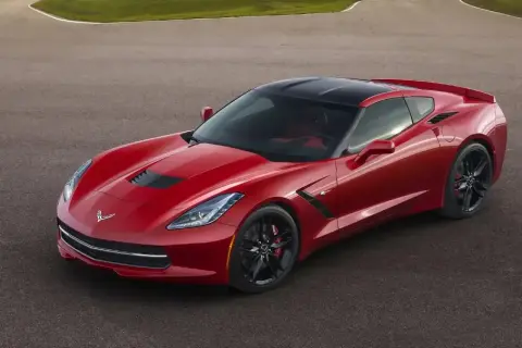 Czerwony Chevrolet Corvette Stingray z czarnym dachem na torze wyścigowym.