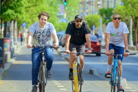 Drei Freunde fahren nebeneinander Fahrrad auf einer Straße.