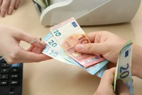 Ręce przekazują sobie banknoty euro. Czy na Węgrzech można płacić euro? Tak, euro jest powszechnie akceptowane.