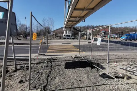 Przejście dla pieszych w budowie, ogrodzone siatką. W tle wiadukt i ruch uliczny. Kmy rejestracja.