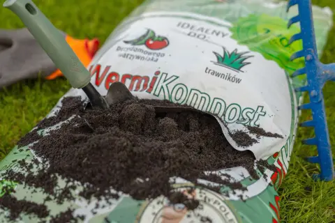 Łopatka nabiera żyzny wermikompost z worka, gotowa do użycia w ogrodzie.
