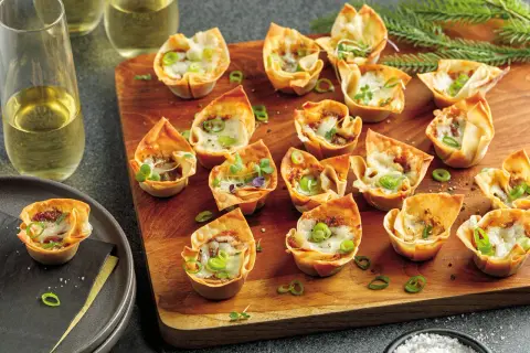 Petits feuilletés croustillants garnis d'effiloché de canard en feuille de brick, parsemés de ciboule et de fromage fondu.