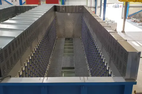 Duży, metalowy zbiornik przemysłowy z rzędami niebieskich elementów i kratownicami.