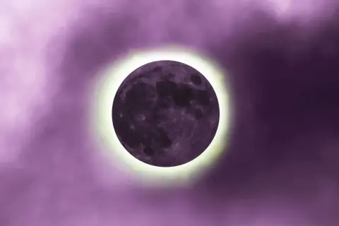 Luna nueva en tonos morados, con un halo brillante. Representa el inicio de ciclos y el luna nueva significado espiritual.