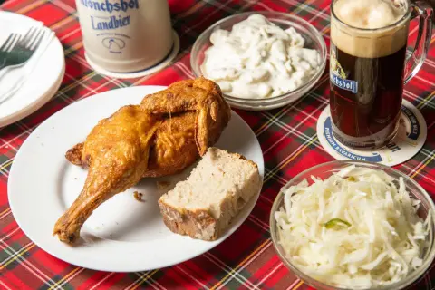 Knusprige Henne Berlin mit Brot, Krautsalat und einem Bierkrug.
