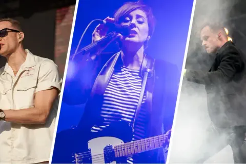 Artyści na scenie podczas letnich brzmień we Wrocławiu. Mężczyzna w okularach śpiewa, kobieta gra na gitarze, a kolejny mężczyzna w garniturze tańczy w dymie.