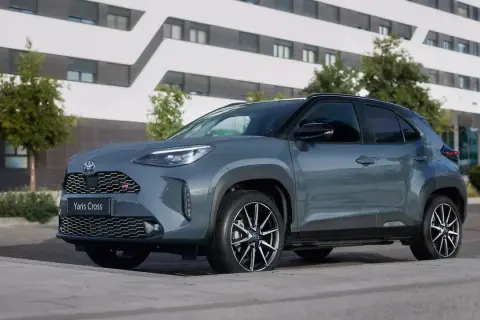 Szary Toyota Yaris Cross benzyna z czarnymi akcentami stoi przed nowoczesnym budynkiem.