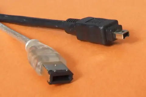 Dwa kable: jeden przezroczysty z szeroką wtyczką, drugi czarny z małą wtyczką. To złącza FireWire IEEE 1394.