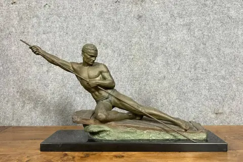 Sculpture d'un athlète en mouvement, tenant une lance. L'œuvre en bronze ou régule, est posée sur un socle en marbre noir.