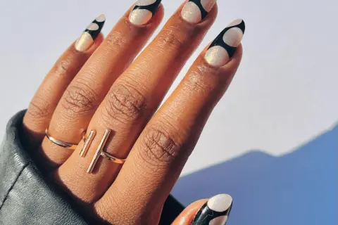 Unghie lunghe e affusolate con decorazione a pois bianchi e neri, realizzate con acrygel. Brillanti e alla moda.