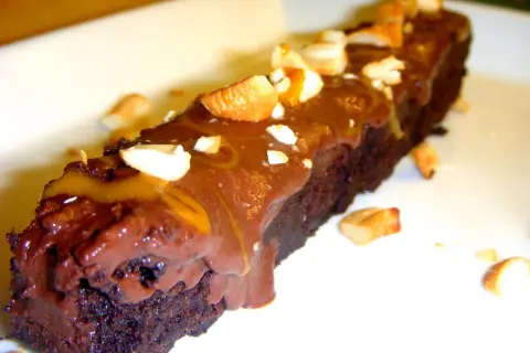 En bit fransk chokladtårta med chokladglasyr och nötter.