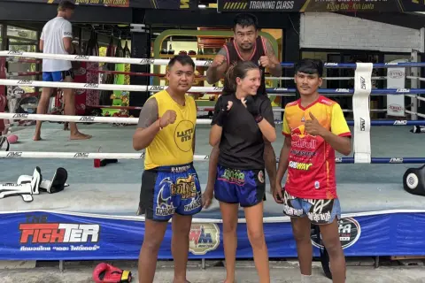 Fyra personer poserar i en ring för c4 thaiboxning. En kvinna i mitten med tränare på var sin sida.
