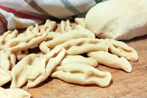 Strascinati pugliesi freschi, pronti per essere cucinati, su un tagliere di legno.