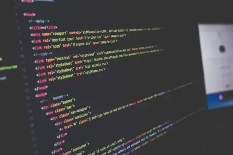 Code informatique affiché sur un écran, avec des lignes de HTML et CSS. Le logiciel Scilab est utilisé pour le développement.