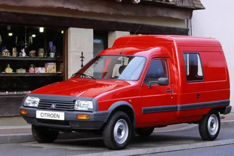 Czerwony Citroen C15, dostawczy klasyk, parkuje przed sklepem z upominkami.