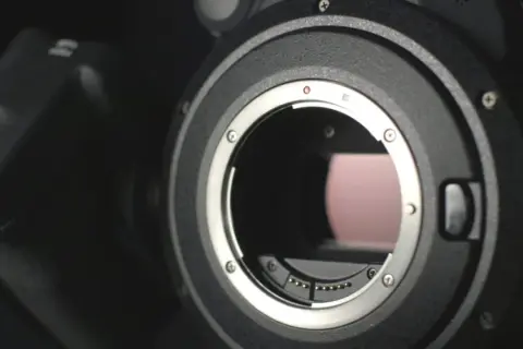 Dettaglio obiettivo di una fotocamera ad alta megapixel, con il pulsante REC visibile.