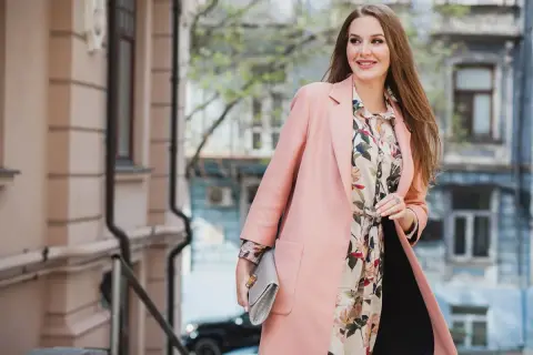 Elegancka kobieta w pastelowym płaszczu i kwiecistej sukience. Idealny strój na 14 stopni, gdy chcesz wyglądać stylowo.