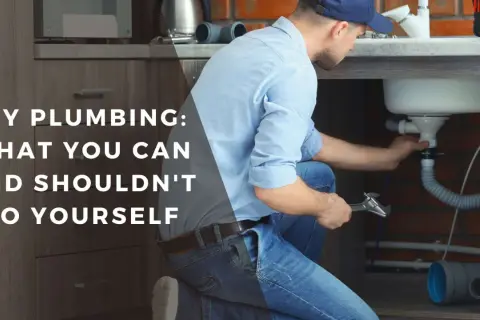 Man working on sink plumbing, part of a DIY bathroom remodel guide.