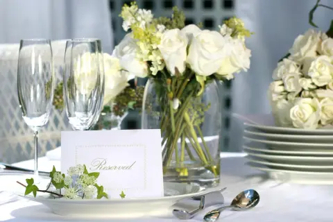 Elegancko nakryty stół z białymi różami, kieliszkami i kartą "Reserved". Idealny na przyjęcie, gdzie wedding planner cena jest kluczowa.