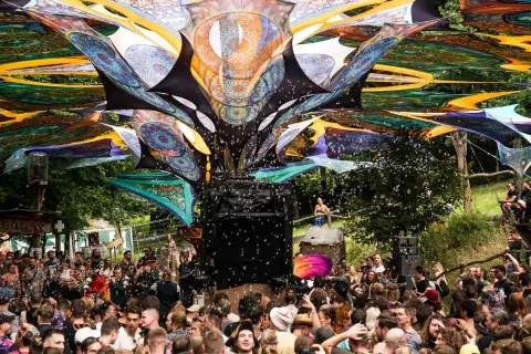 Bunte Stoffbahnen überspannen die Menge auf dem Wunderland Festival. Seifenblasen steigen auf, während die Besucher tanzen.