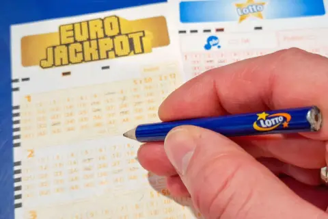 Dłoń z ołówkiem Lotto na kuponie Eurojackpot. Zastanawiasz się, dlaczego los w Eurojackpot w Polsce jest droższy?