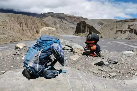 Plecak czeka na dalszą drogę. W tle majestatyczne góry i rzeka, idealne miejsce na trekking w Himalajach.