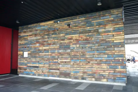 Un mur en palette extérieure aux couleurs vives et variées, créant une texture unique.