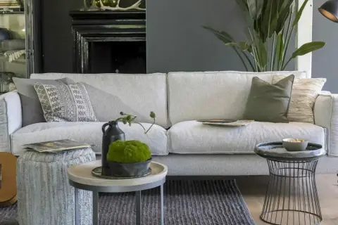 Ein hellgraues Sofa mit verschiedenen Kissen. Die Frage, welche Sofa-Polsterung die beste ist, wird hier stilvoll beantwortet.