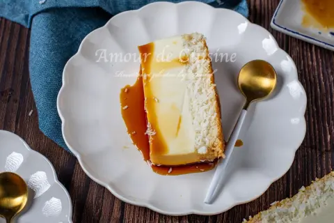 Tranche de flan coco antillais onctueux, nappé de caramel, avec une croûte de noix de coco râpée. Une cuillère dorée est posée à côté.