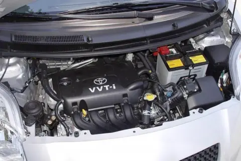 Silnik Toyoty Yaris II z widocznym akumulatorem i elementami osprzętu.