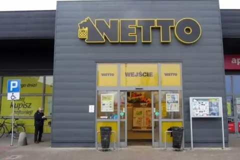 Wejście do sklepu Netto. Obok parking dla niepełnosprawnych. Aplikacja Netto pomoże Ci znaleźć najlepsze okazje.
