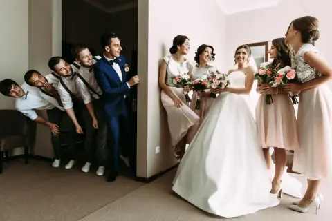 Bräutigam und Trauzeugen stehen Spalier, während die Brautjungfern mit Blumensträußen auf die Braut warten. Eine lustige Szene, die die **Trauzeugen Pflicht** humorvoll darstellt.