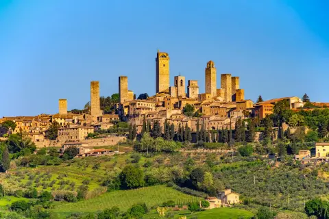 San Gimignano z wieżami, otoczone zielonymi wzgórzami Toskanii, gdzie dojrzewają winogrona na wino Vernaccia di San Gimignano.