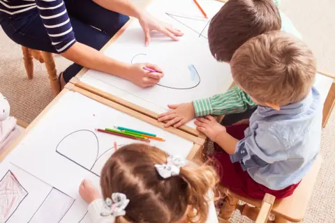 Kinder malen und lernen spielerisch im Kindergarten. Bunte Stifte und viel Kreativität bei den Sprachspielen.