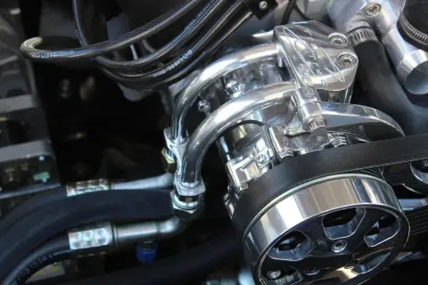Detalle de un motor con piezas cromadas brillantes y cables. Se escucha un leve traqueteo en el motor, quizás por la tensión de la correa.