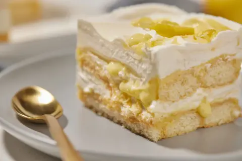 Ein Stück cremiges Lemon Tiramisu mit Löffel auf einem Teller.