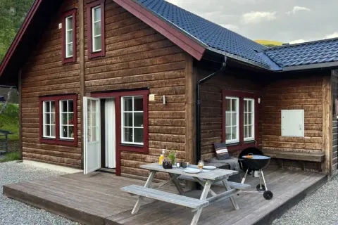 Mysig trästuga med grill och picknickbord på altanen, perfekt för en avkopplande vistelse på buskvallen inn.