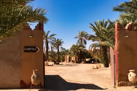 Ein Tor führt zu einem Campingplatz in Marokko, umgeben von Palmen. Ja, ist Marokko sicher für Reisende.