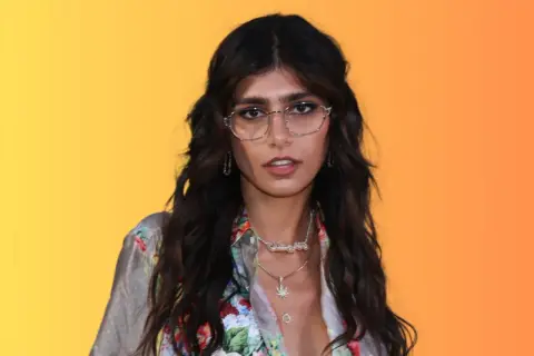 Mia Khalifa w okularach i kwiecistej koszuli, z naszyjnikami, wygląda jakby szykowała się do nagrania nowego mia khalifa song.