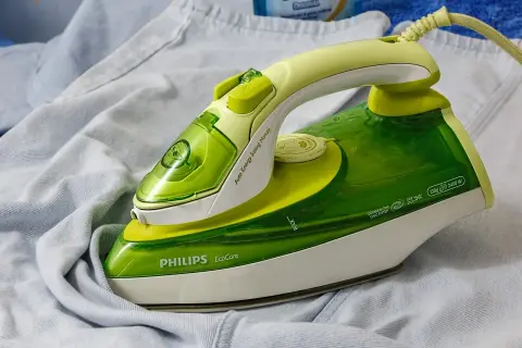 Zielone żelazko Philips EcoCare na jasnych ubraniach. Dowiedz się, jak wyczyścić żelazko, by prasowanie było efektywne.