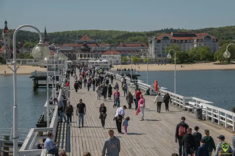 Spacer po molo w Sopocie, gdzie tłumy ludzi korzystają z pięknej pogody. To świetne miejsce na relaks i odkrywanie **Gdańsk atrakcje dla młodzieży**.