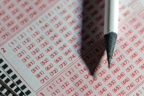 Zbliżenie na kupon lotto z zaznaczonymi liczbami i ołówkiem.